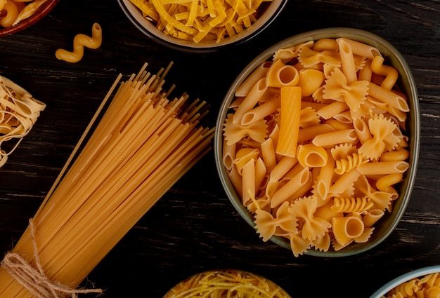 Vista superior de diferentes tipos de pasta como cavatappi spaghetti vermicelli tagliatelle y otros sobre superficie de madera