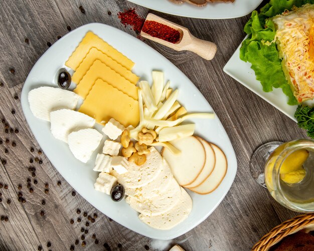 Vista superior de diferentes tipos de queso en un plato blanco sobre la mesa