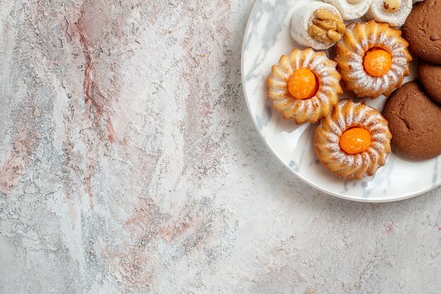 Vista superior de diferentes tortas dulces pequeños en el fondo blanco galleta de té galleta pastel dulce de azúcar