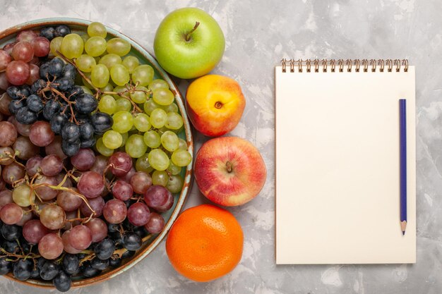 Vista superior de diferentes uvas con otras frutas en el escritorio blanco claro