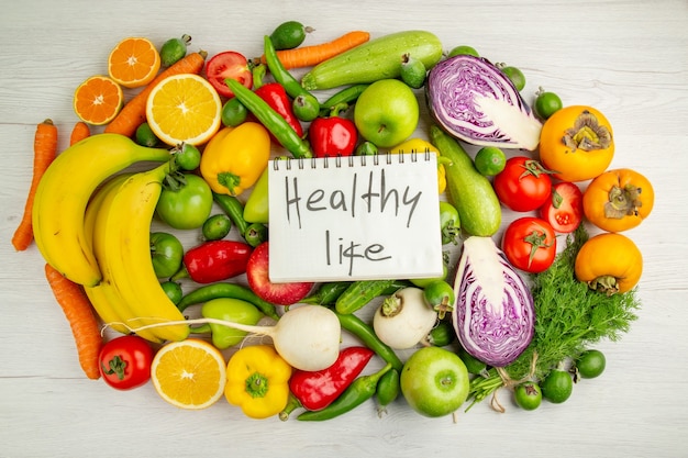 Vista superior de diferentes verduras con frutas sobre fondo blanco dieta ensalada salud color maduro