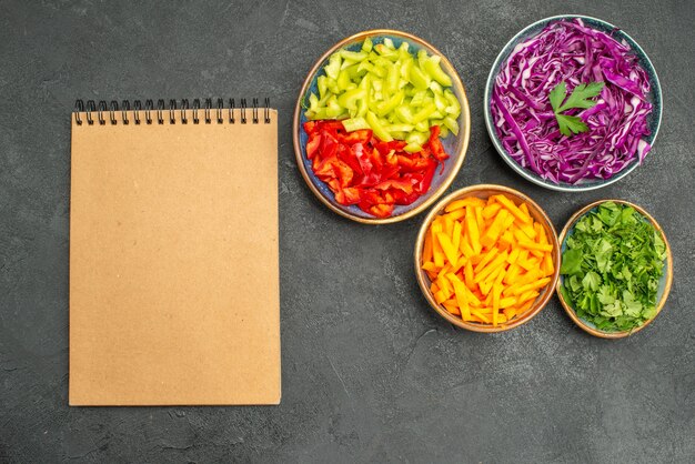 Vista superior de diferentes verduras en rodajas con verduras en la dieta saludable de la mesa oscura