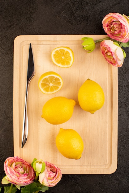 Una vista superior distante limones frescos amargos maduros enteros y en rodajas cítricos suaves vitamina amarilla amarilla en el oscuro escritorio