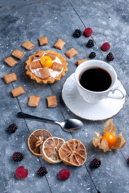 Vista superior distante taza de café con cremoso pastel almohada formada galletas junto con bayas en el escritorio gris, baya galleta galleta