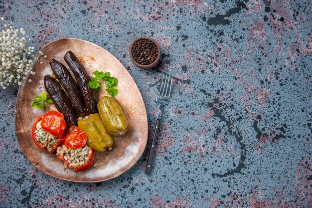 Vista superior dolma de berenjena con tomates cocidos y pimientos rellenos con carne molida dentro de la placa, comida de cena de color de alimentos