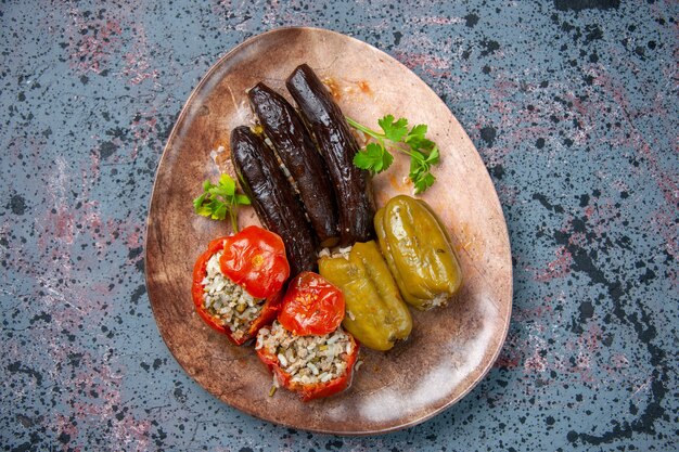 Vista superior dolma de berenjena con tomates cocidos y pimientos rellenos con carne molida dentro de la placa, comida de la cena color