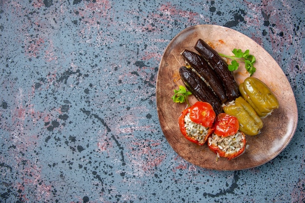 Vista superior dolma de berenjena con tomates cocidos y pimientos rellenos con carne molida dentro de la placa, plato de cena de color