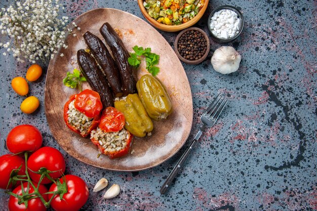 Vista superior dolma de berenjena con tomates cocidos y pimientos rellenos con carne molida dentro de la placa, plato de colores de comida