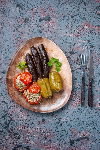 Vista superior dolma de berenjena con tomates cocidos y pimientos rellenos con carne molida dentro de la placa, plato de comida color de comida