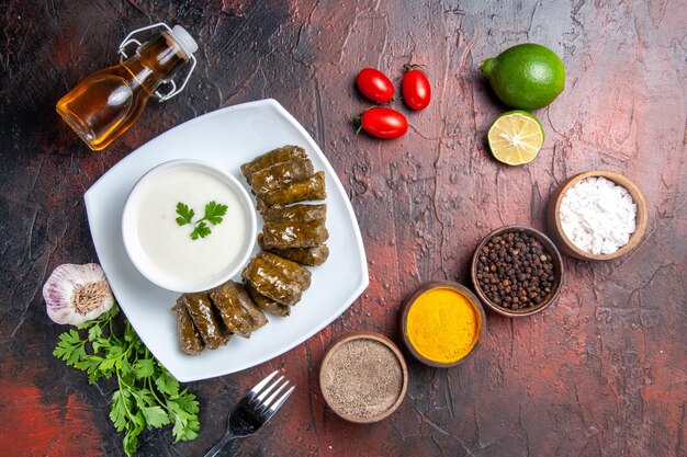 Vista superior de la dolma de hoja verde con condimentos en la superficie oscura