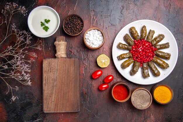 Vista superior de la dolma de hoja verde con condimentos en la superficie oscura