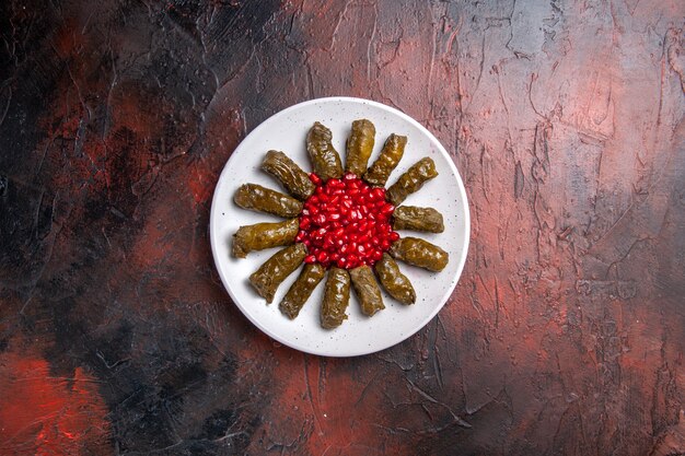 Vista superior de dolma de hoja verde con granadas en superficie oscura