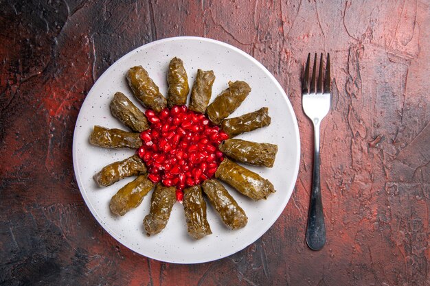 Vista superior de dolma de hoja verde con granadas en superficie oscura