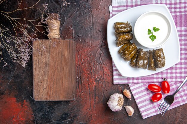 Vista superior de dolma de hoja verde con yogur en la superficie oscura