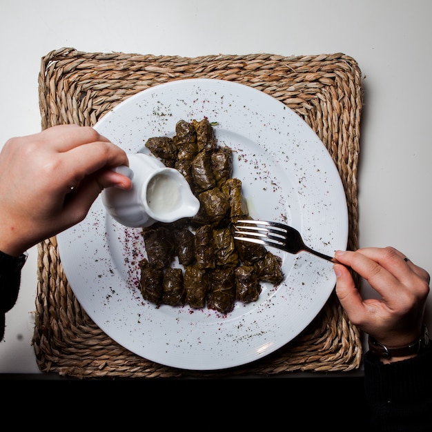 Foto gratuita vista superior dolma con yogurt y tenedor y mano humana en servilletas