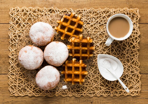 Vista superior de donas con azúcar en polvo y waffles