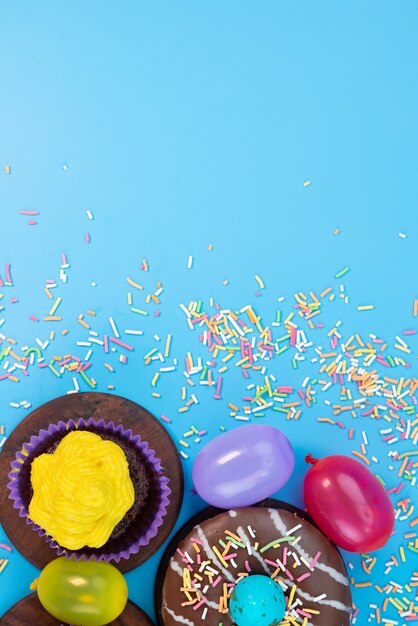 Una vista superior de donas y brownies deliciosos y basados en chocolate junto con caramelos en azul, color de galleta de pastel de caramelo