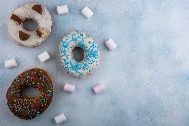 Vista superior de donas dulces con malvaviscos en una mesa gris