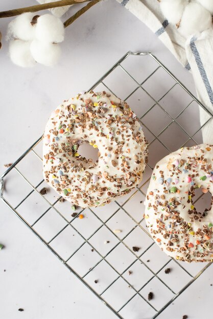 Vista superior de donas glaseadas con chispas y flor de algodón