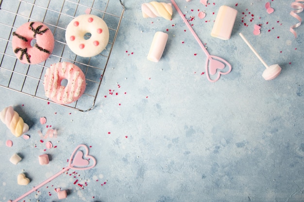 Foto gratuita vista superior de donas glaseadas con una variedad de dulces y malvaviscos