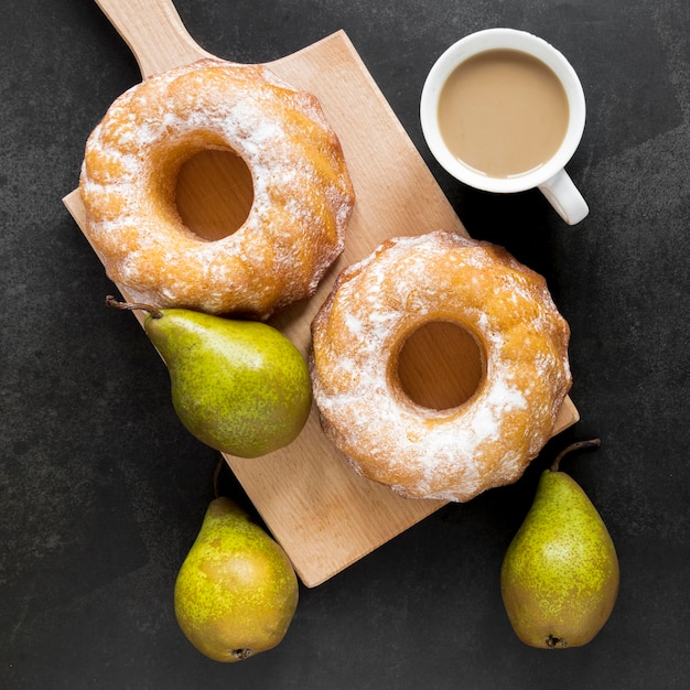 Vista superior de donas en tabla de cortar con peras y café