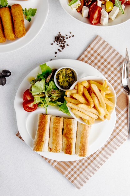 Vista superior de doner en lavash con papas fritas y ensalada fresca en placa