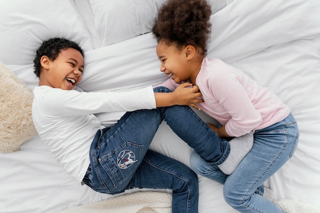 Foto gratuita vista superior de dos hermanos jugando juntos en la cama en casa