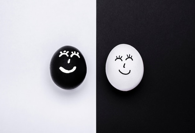Vista superior de dos huevos de diferentes colores con caras para movimiento de materia de vidas negras