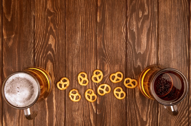 Vista superior de dos jarras de cerveza con mini pretzels en tela de saco rústico con espacio de copia