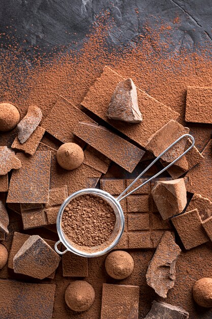 Vista superior de dulces y chocolate con tamiz y cacao en polvo