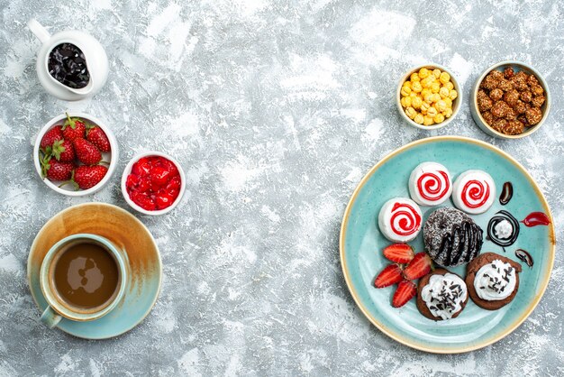 Vista superior dulces deliciosas galletas con taza de café sobre fondo blanco galleta pastel de azúcar galleta dulce