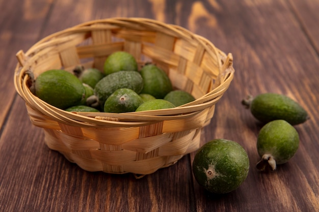 Vista superior de dulces feijoas tropicales en un balde con feijoas aislado en una pared de madera