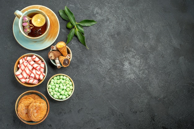 Vista superior de dulces una taza de té galletas dulces coloridos cítricos con hojas