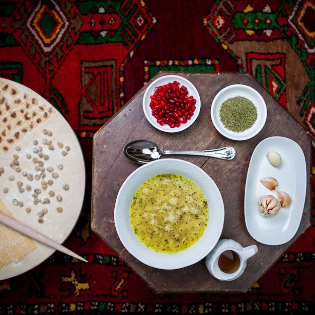 Foto gratuita vista superior dushpara con semillas de granada y vinagre y tablero de masa en la mesa