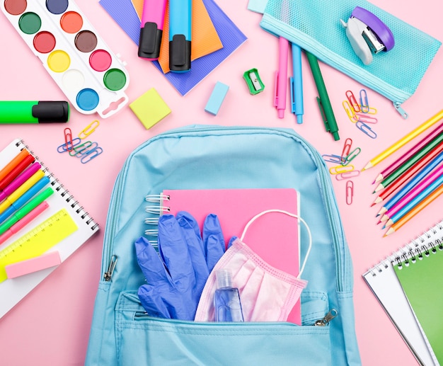 Vista superior de los elementos esenciales de regreso a la escuela con mochila y acuarela