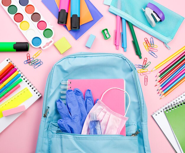 Vista superior de los elementos esenciales de regreso a la escuela con mochila y acuarela