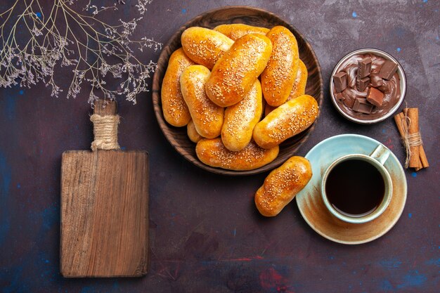 Vista superior empanadas dulces con taza de té y chocolate sobre fondo oscuro masa de pastelería comida comida empanada