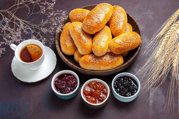 Vista superior de empanadas dulces con té y mermelada sobre fondo oscuro, comida de té, pastelería, masa de empanada, comida