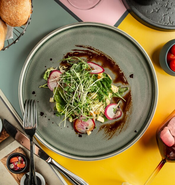 Vista superior de ensalada de aguacate con rábano, pimiento amarillo y hierbas frescas