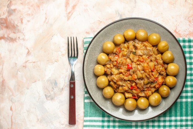 Vista superior de ensalada de berenjena asada y ciruelas en escabeche en placa sobre superficie a cuadros blanco turquesa