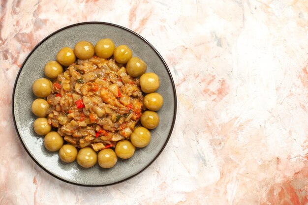 Vista superior de ensalada de berenjena asada y ciruelas en escabeche en placa sobre superficie desnuda