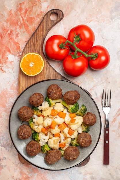 Vista superior de ensalada de brócoli y coliflor y albóndigas en la placa rodaja de limón en la tabla de cortar un tenedor tomates sobre fondo aislado desnudo