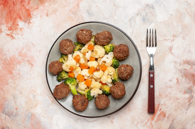 Foto gratuita vista superior de ensalada de brócoli y coliflor y albóndigas en un plato un tenedor en el espacio libre de fondo aislado desnudo