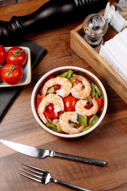 Vista superior de ensalada de camarones con pimientos verdes y tomates en un tazón