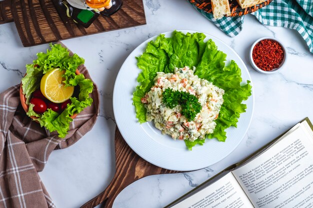 Vista superior ensalada capital en lechuga con pan y una rodaja de limón sobre la mesa