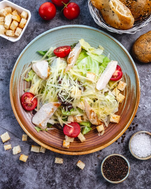 Vista superior de ensalada César de pollo con lechuga, tomate cherry relleno de pan y parmesano