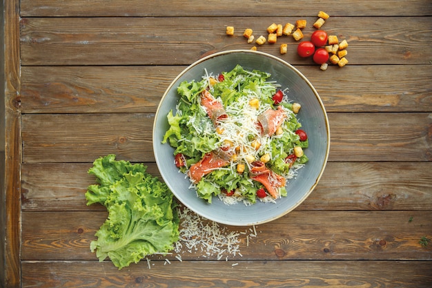 Vista superior de ensalada César con salmón ahumado y queso rallado