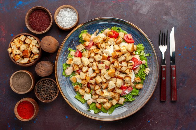 Vista superior ensalada César con verduras en rodajas y bizcochos dentro de la placa en la pared oscura ensalada de verduras comida almuerzo comida tostada sabor