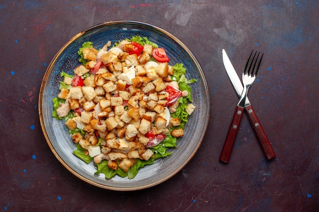 Vista superior ensalada César con verduras en rodajas y bizcochos dentro de la placa en la pared oscura Ensalada de verduras comida almuerzo comida tostada sabor