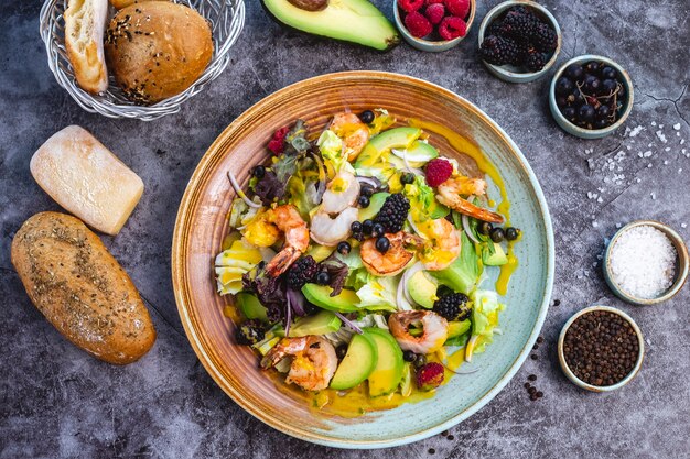 Vista superior de ensalada de dieta saludable con camarones fritos, aguacate, lechuga, cebolla roja y bayas